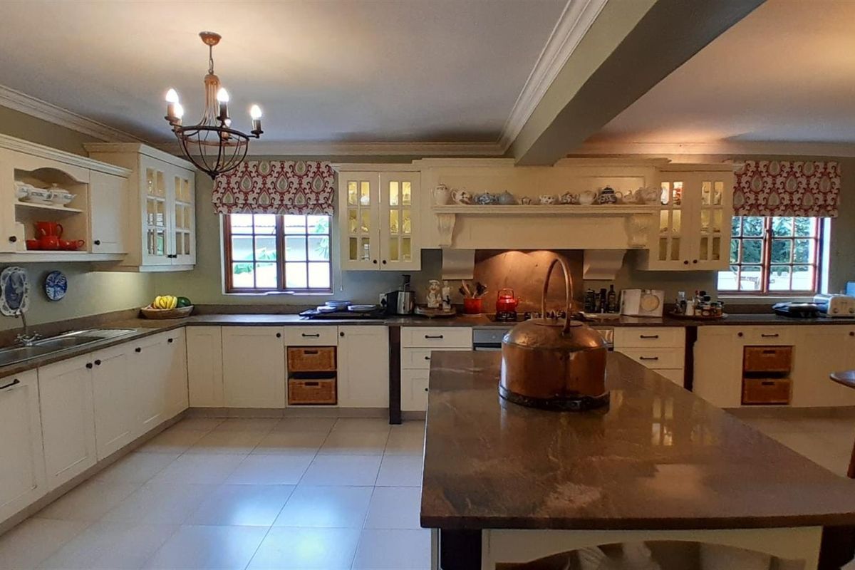 Spacious country-style kitchen featuring cream cabinetry, a large central island with a stone countertop, and integrated cooking appliances.