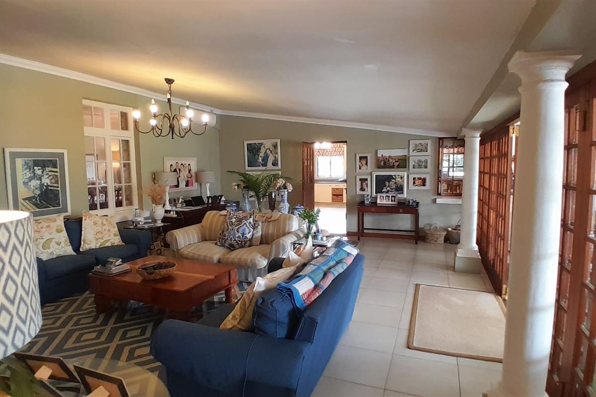Spacious living room featuring tiled flooring, decorative columns, and large wooden framed glass doors leading to the exterior.