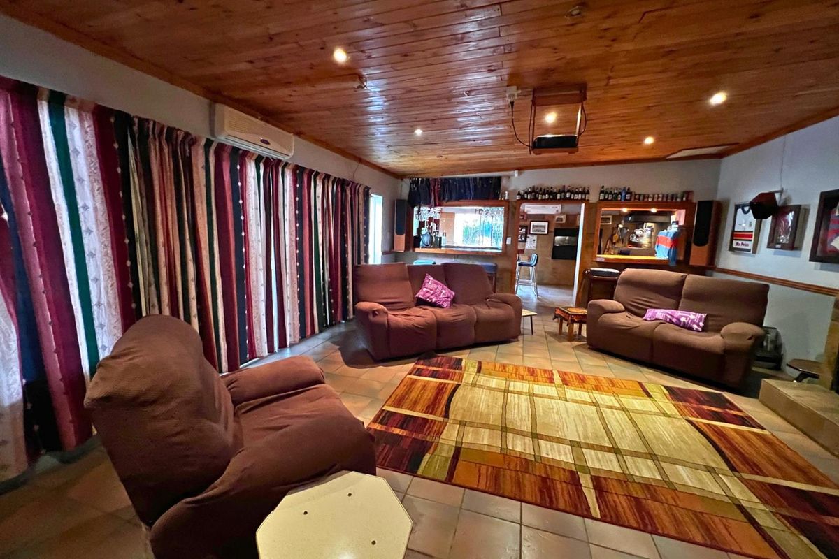 Spacious living area featuring a timber-clad ceiling, tiled flooring, and a built-in bar counter, creating a relaxed entertainment space.