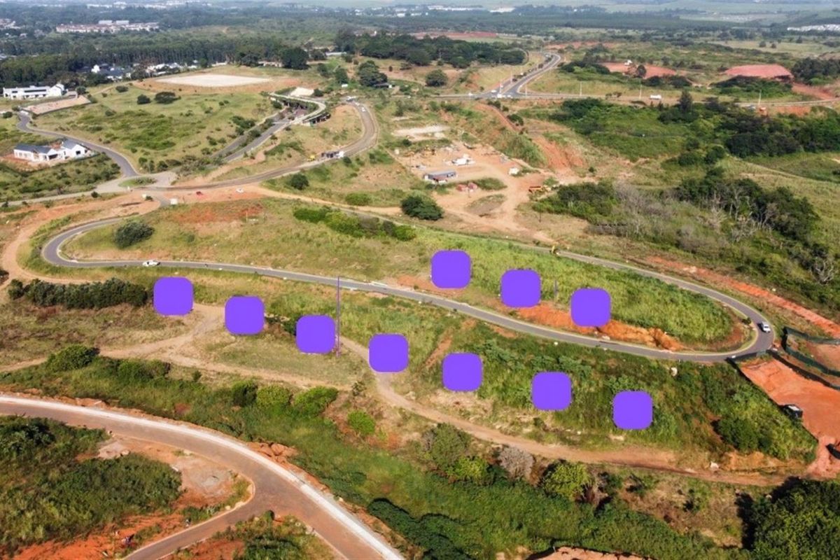 Aerial view of a vacant residential development site featuring cleared land, established road infrastructure, and surrounding natural landscape.