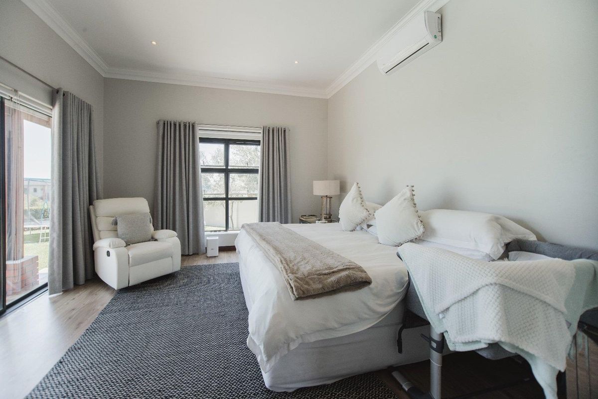 A well-maintained bedroom featuring neutral walls, coving, recessed lighting, a split-system air conditioner, and large sliding glass doors providing natural light.