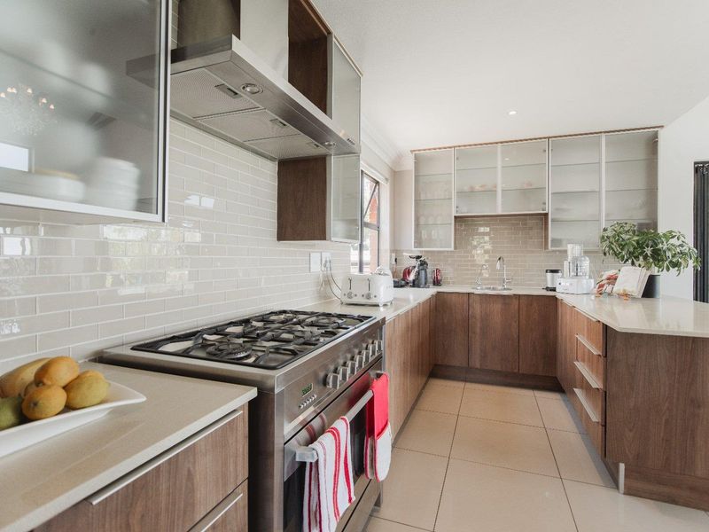 Modern kitchen featuring wood-finish cabinetry, stone countertops, a gas range with stainless steel extractor, and a subway tile backsplash.