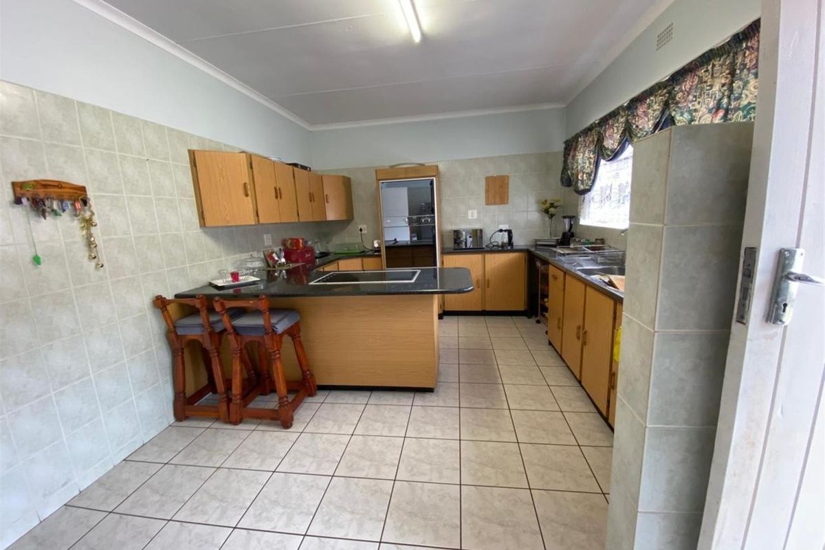 A functional kitchen featuring tiled flooring, ample wooden cabinetry, a breakfast bar, and integrated oven, offering a practical layout for daily meal preparation.