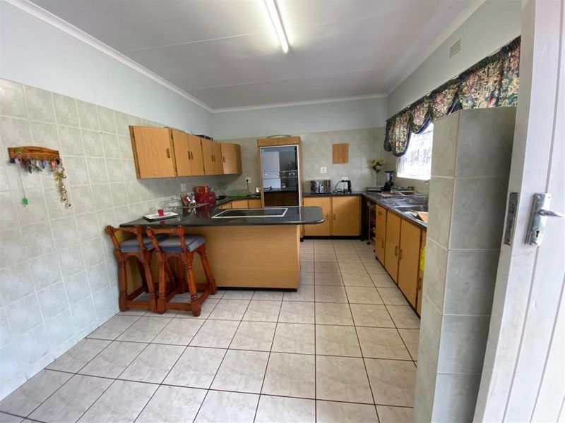 A functional kitchen featuring tiled flooring, ample wooden cabinetry, a breakfast bar, and integrated oven, offering a practical layout for daily meal preparation.
