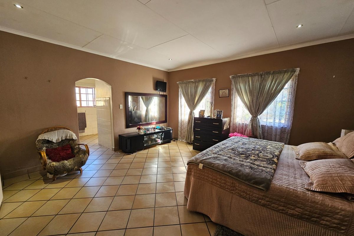 Spacious bedroom featuring tiled flooring, recessed downlighting, and an arched doorway leading to an adjoining bathroom area.