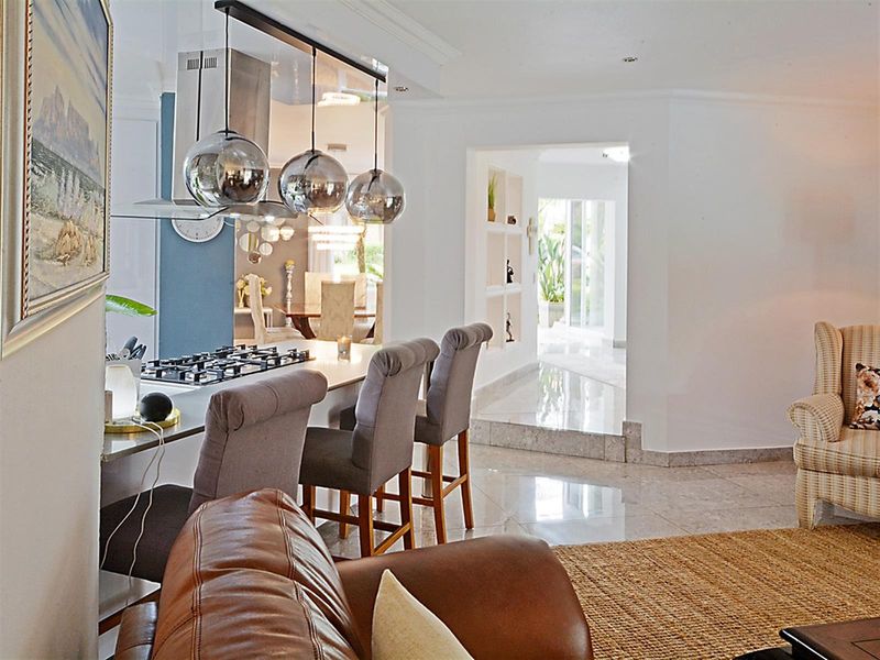 Open plan living area featuring a modern kitchen island with gas hob, extractor fan, and polished tile flooring leading to an adjacent dining space.