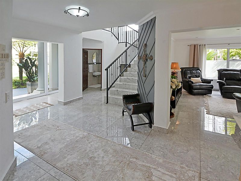 Spacious entrance hall featuring polished marble flooring, a central staircase with wrought iron balustrades, and seamless flow into the adjacent living area.
