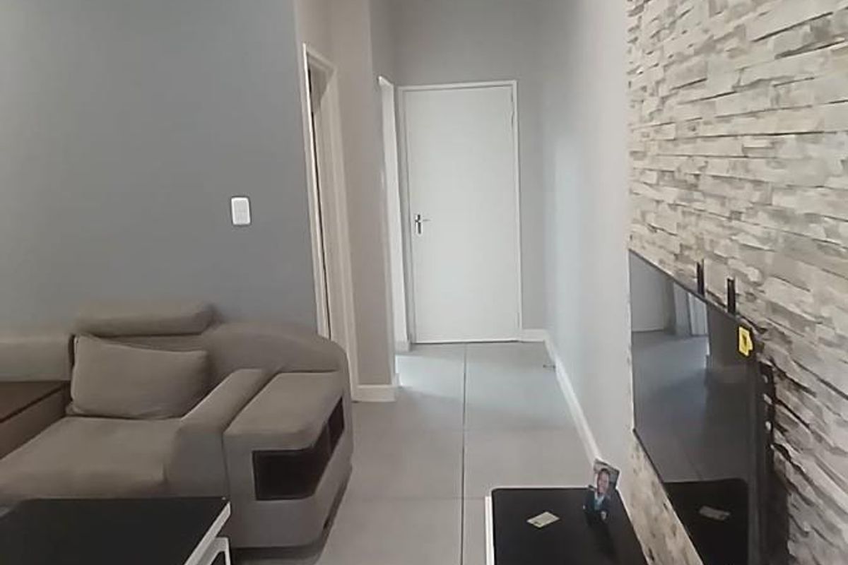 Modern living room featuring large format floor tiles and a textured stone feature wall with a wall-mounted television.