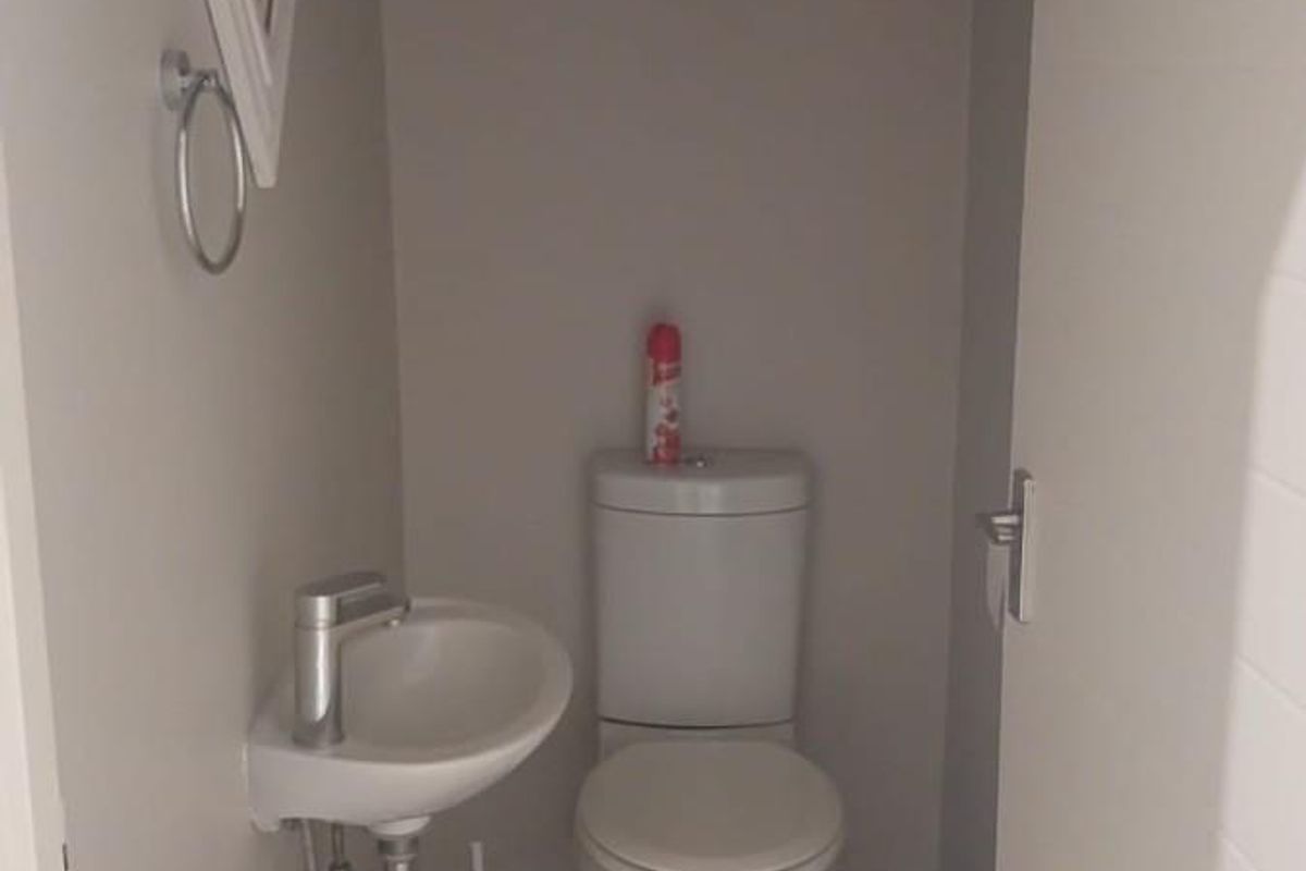A compact guest cloakroom featuring a modern wall-mounted basin and a standard white toilet suite with tiled flooring.