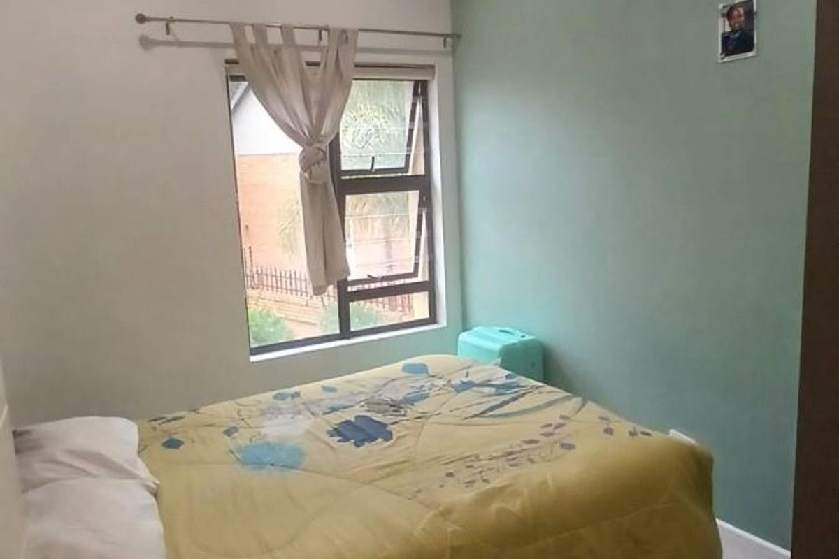 A bedroom featuring tiled flooring, a ceiling fan, and a window with curtain rod.
