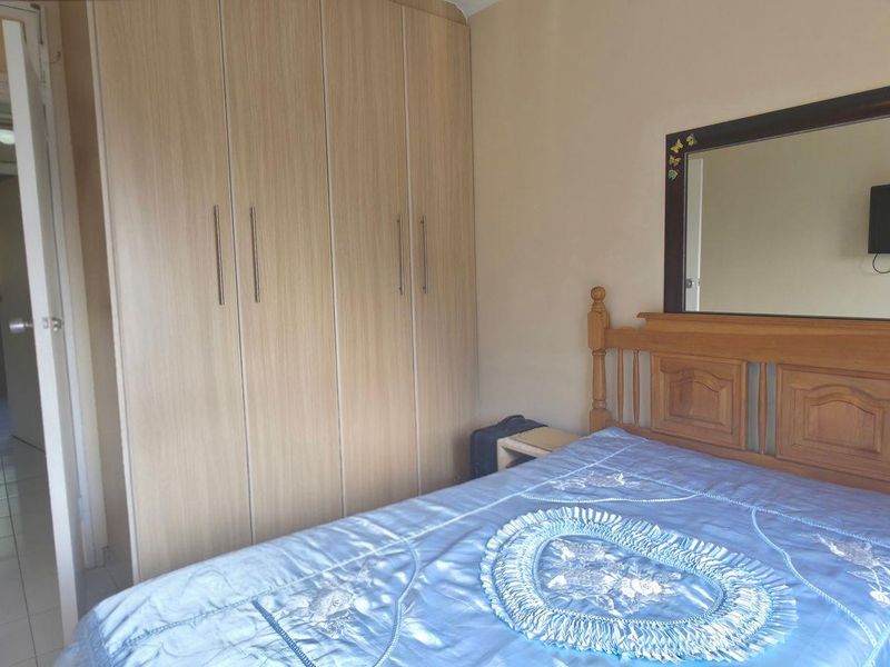 A bedroom featuring a built-in wardrobe and tiled flooring, with a view into the adjacent hallway.