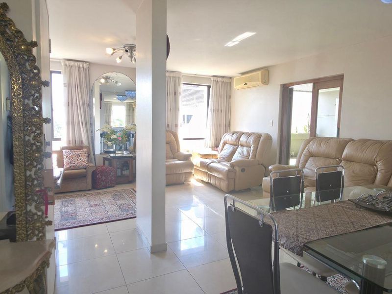 Spacious open-plan living and dining area featuring tiled flooring, split-system air conditioning, and sliding glass doors leading to an outdoor space.
