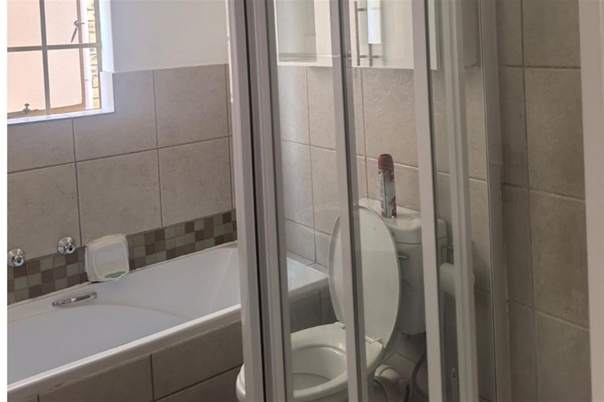A functional bathroom featuring a bathtub, a separate shower enclosure, and a toilet, finished with neutral wall tiling.