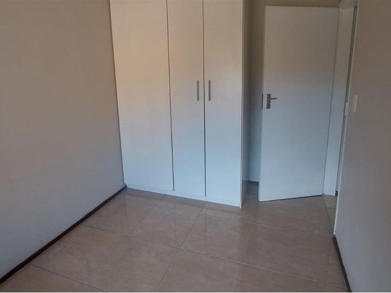 A clean, empty bedroom featuring neutral tiled flooring and white built-in cupboards, offering a blank canvas for personalization.
