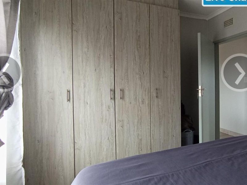 A bedroom featuring built-in wooden cupboards with modern handles and a neutral interior finish.