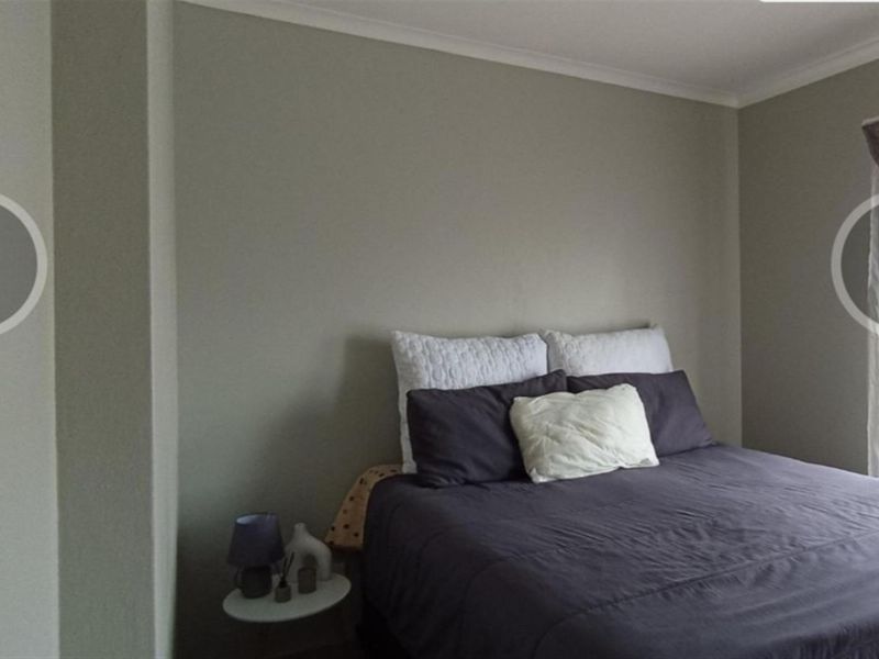 A bedroom featuring neutral wall tones, coved ceiling cornicing, and a window with fitted curtain hardware.