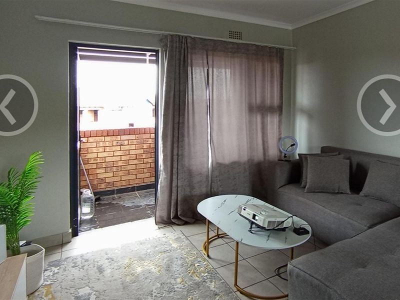 A living room featuring tiled flooring and a glass door providing direct access to an outdoor balcony area.