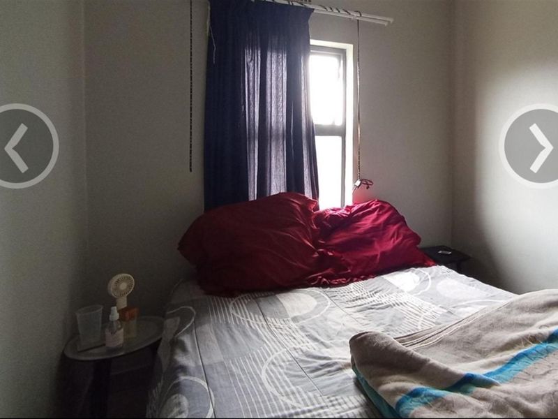 A compact bedroom featuring a single window with basic window treatments and neutral wall finishes.
