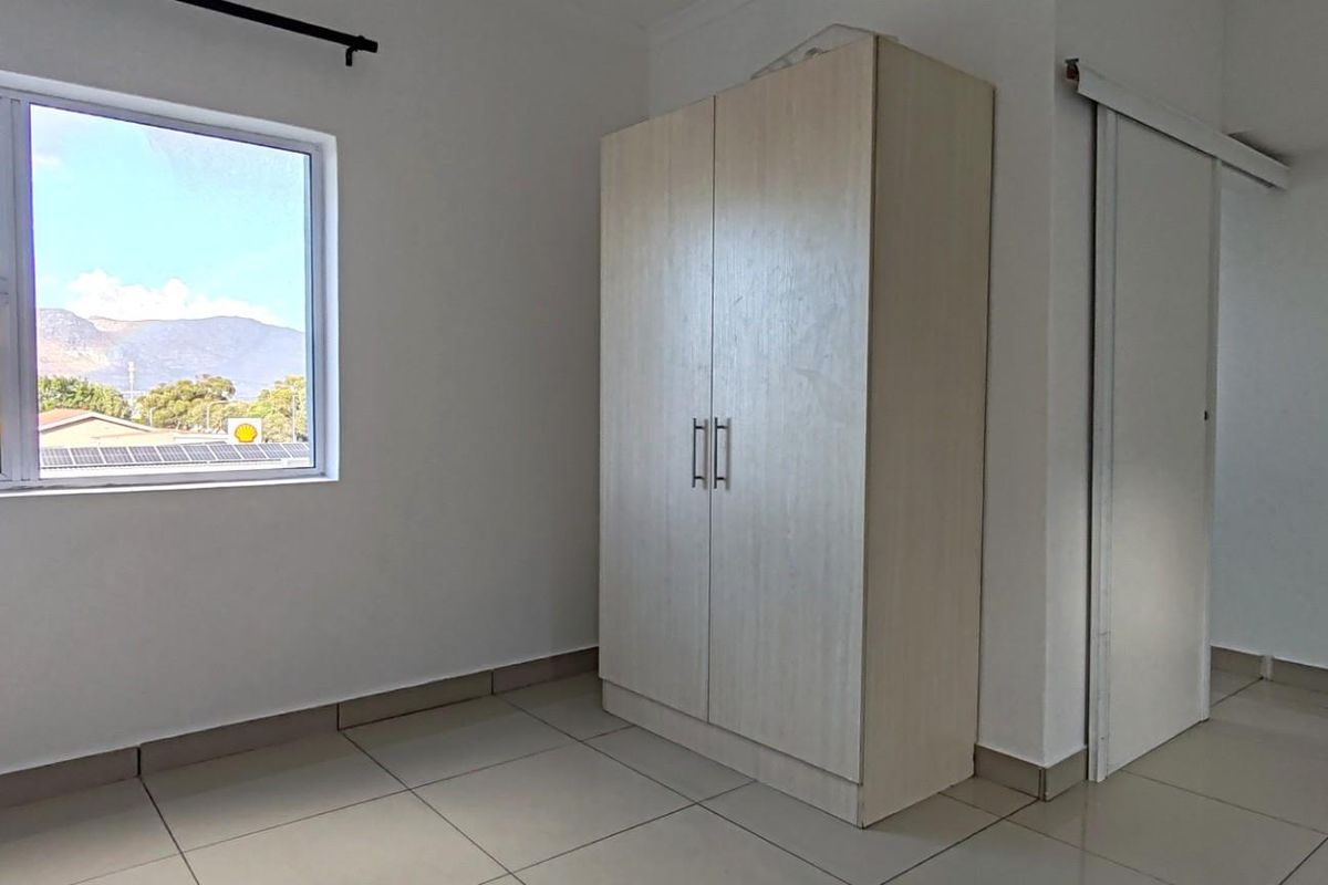 A bright bedroom featuring large windows with mountain views, tiled flooring, and a built-in wardrobe.