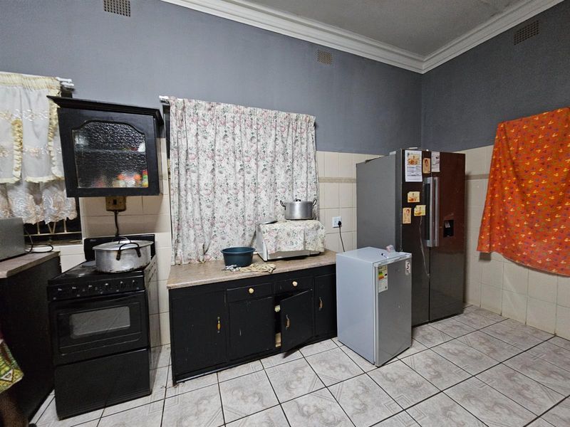 A functional kitchen featuring dark cabinetry, tiled splashbacks, and tiled flooring, offering a practical layout for daily meal preparation.