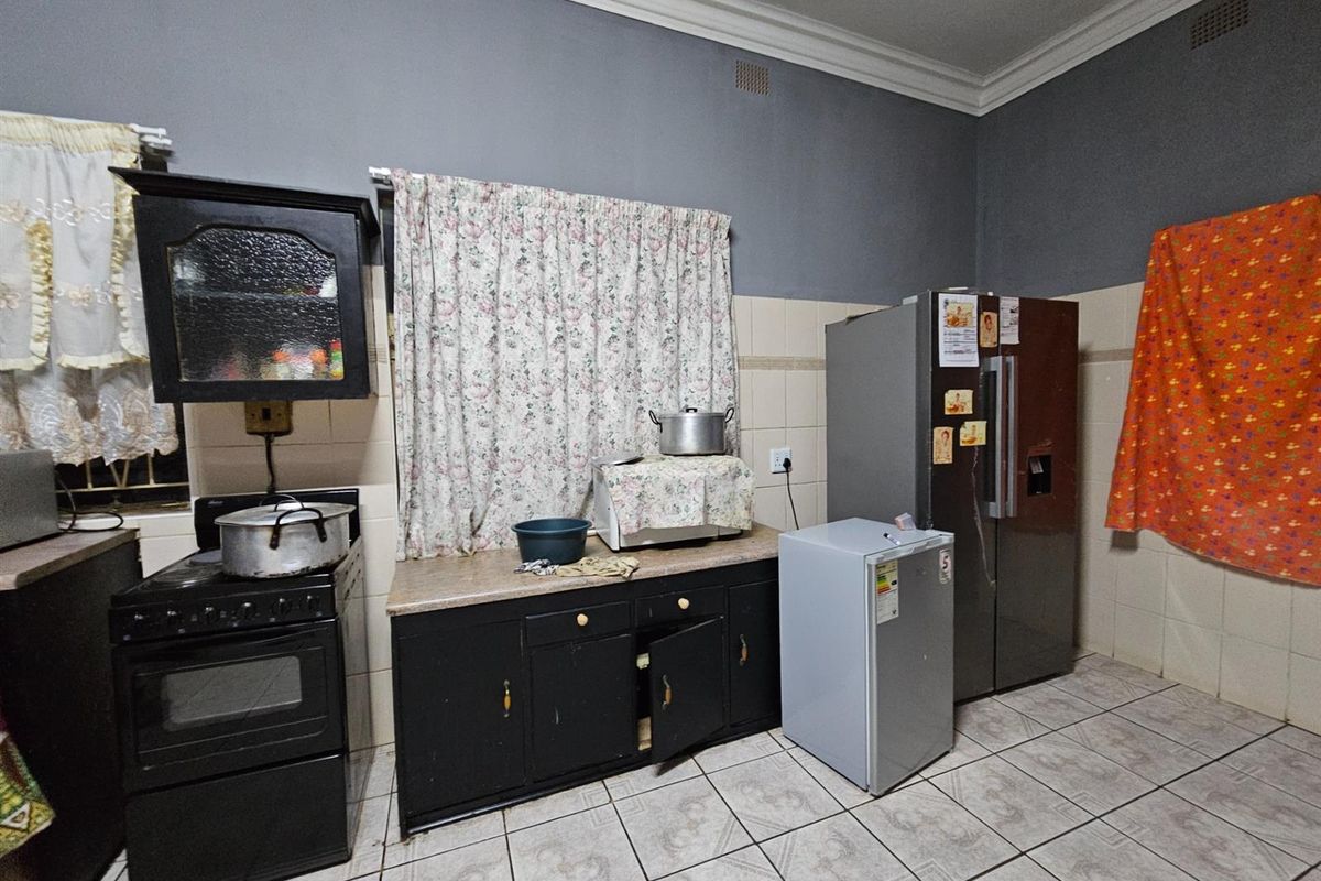 A functional kitchen featuring dark cabinetry, tiled splashbacks, and tiled flooring, offering a practical layout for daily meal preparation.