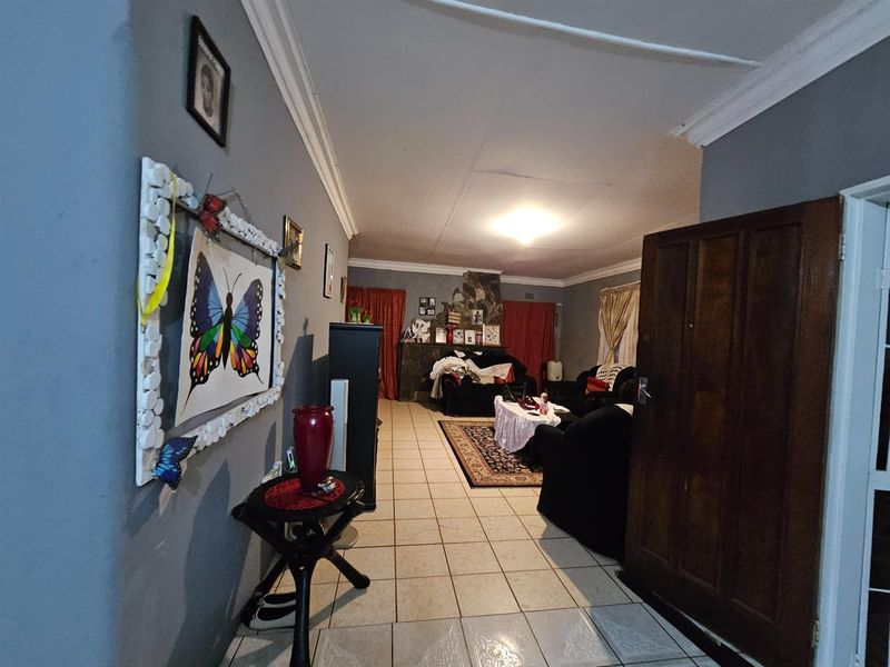 A spacious living room featuring tiled flooring, a built-in fireplace, and crown molding, offering a comfortable and functional living area.