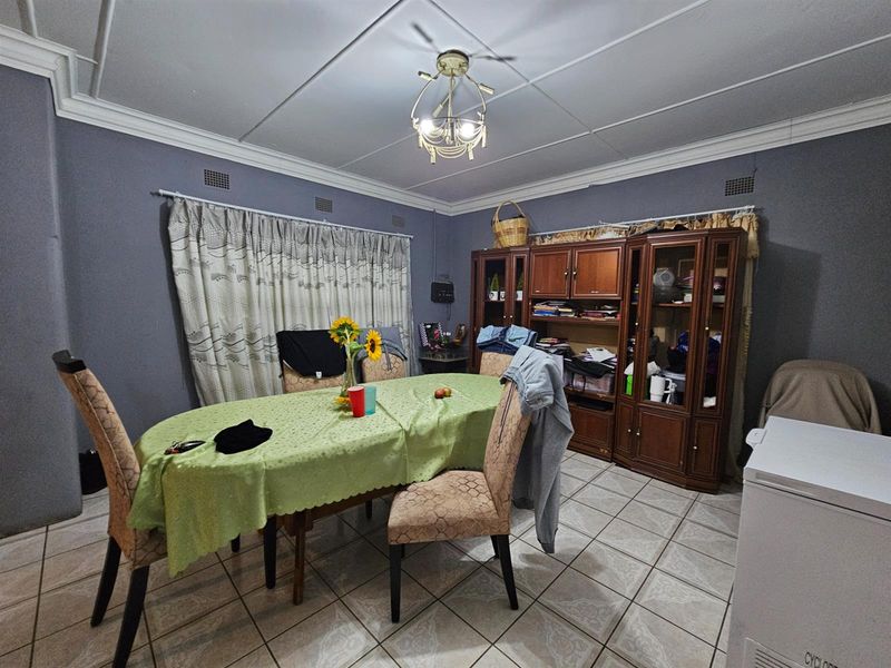 A dining room featuring tiled flooring, decorative ceiling molding, and a central light fixture.