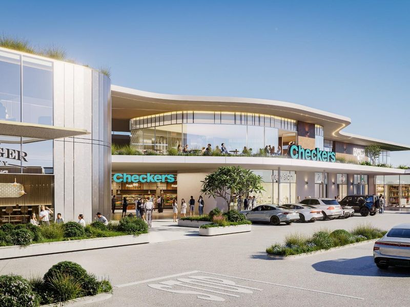 A modern commercial shopping center exterior featuring contemporary glass architecture, integrated retail storefronts, and a landscaped parking area.