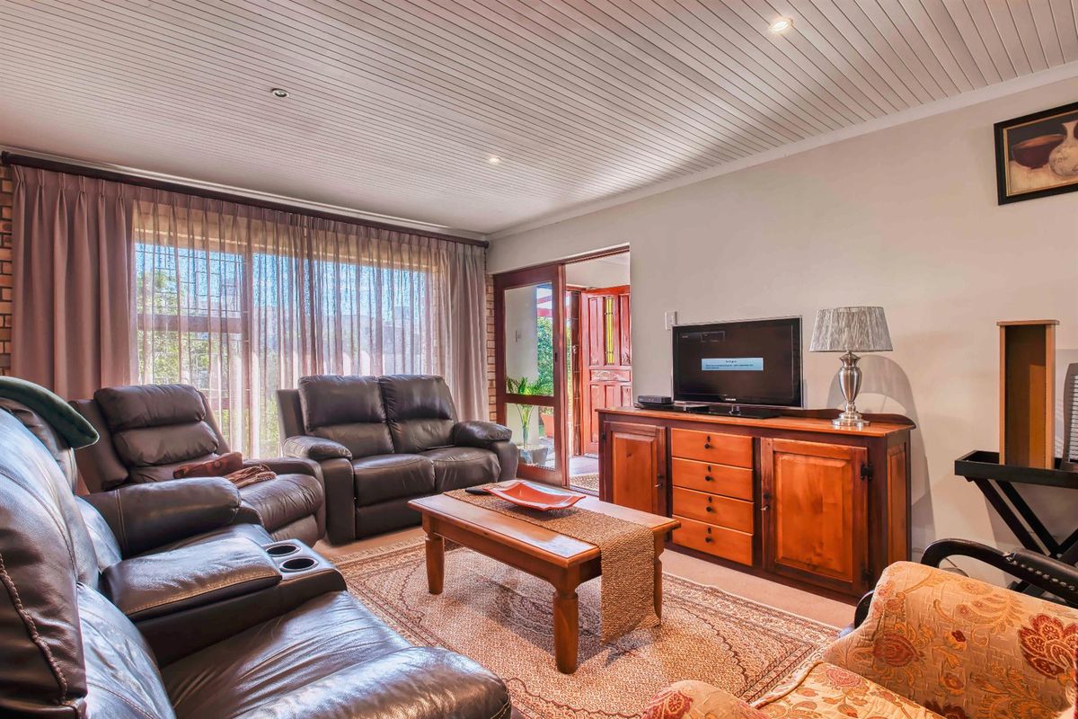 A comfortable living room featuring a tongue-and-groove ceiling, recessed lighting, and large windows that provide natural light and access to the outdoor area.