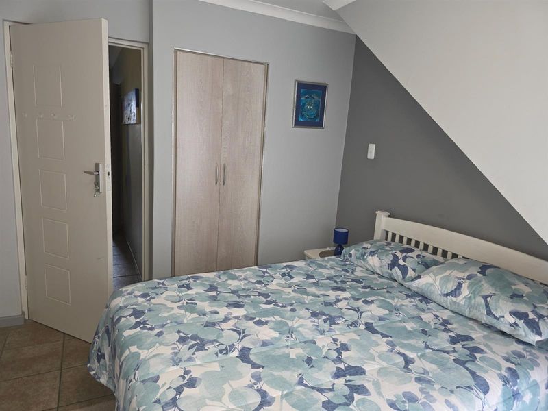 A bedroom featuring a built-in wardrobe, tiled flooring, and a sloped ceiling design.