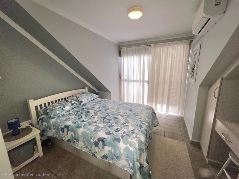 A bedroom featuring a sloped ceiling, tiled flooring, and a wall-mounted air conditioning unit, with direct access to a balcony through sliding glass doors.