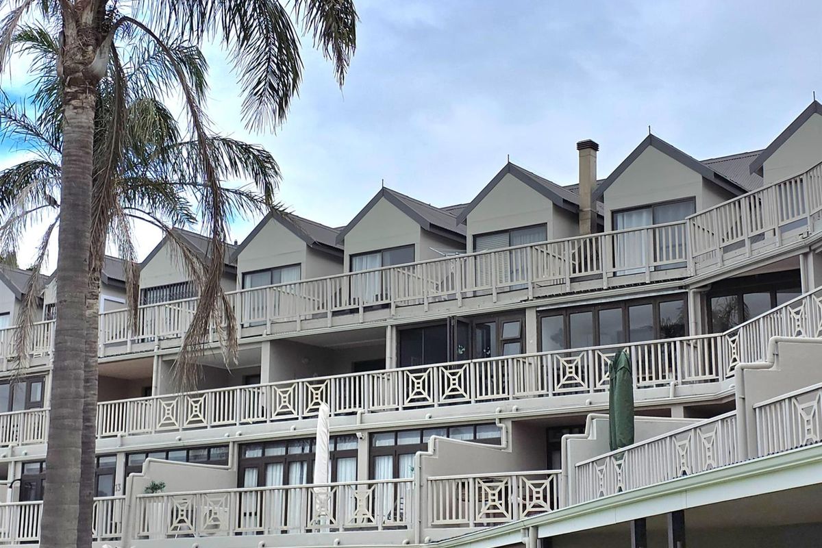 Exterior view of a multi-story apartment complex featuring tiered balconies with decorative railings and large sliding glass doors.