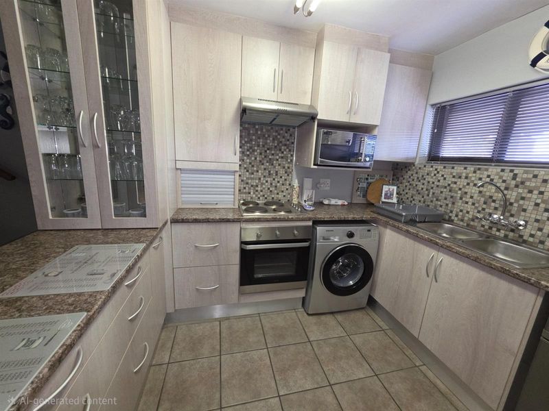 Compact kitchen featuring light wood-grain cabinetry, mosaic tile backsplash, built-in oven, electric hob, extractor fan, and integrated laundry appliance space.