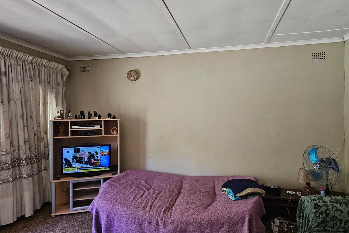 A bedroom featuring a basic layout with a ceiling tile finish and standard window treatments.