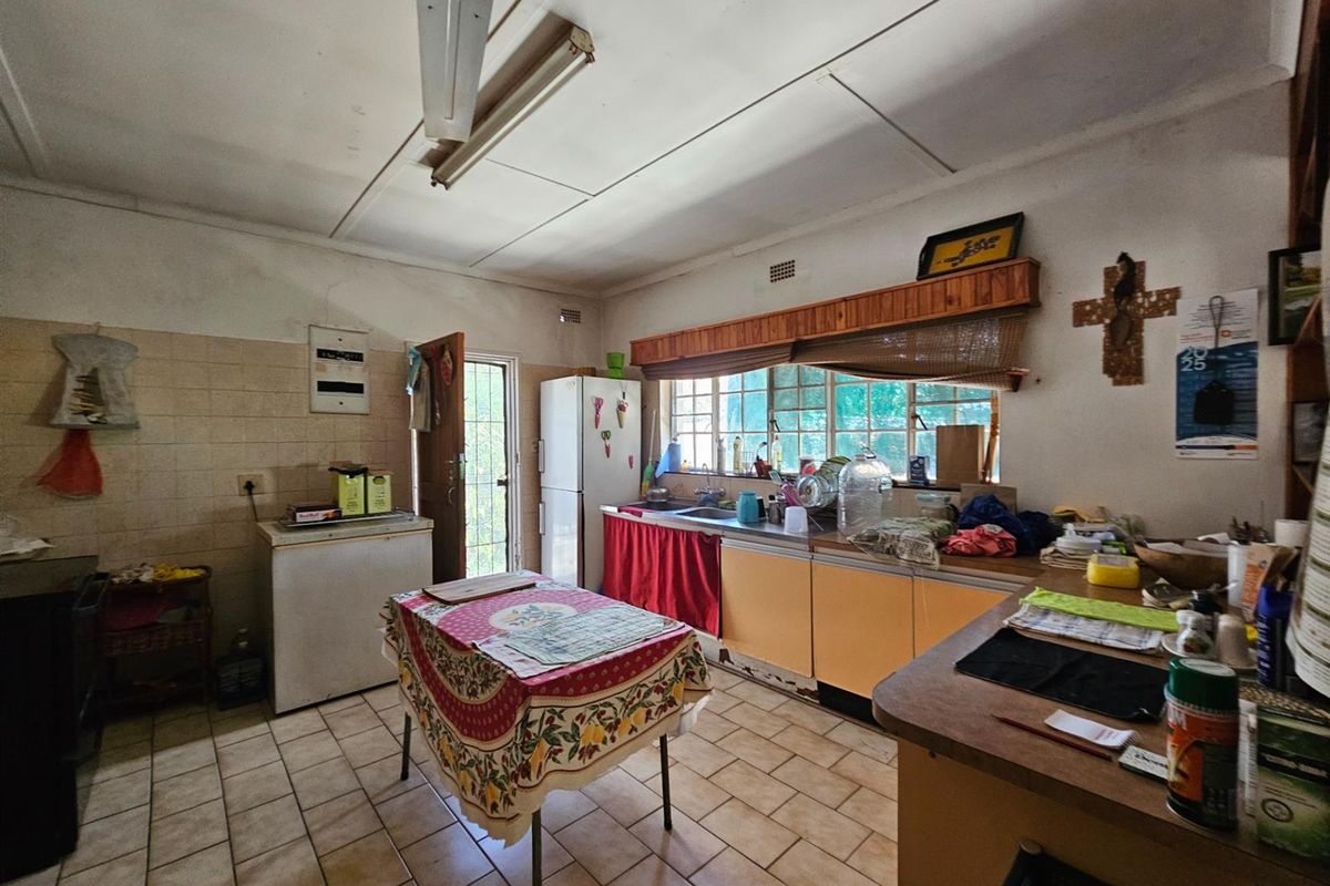 A dated kitchen featuring original cabinetry, tiled flooring, and a functional layout with direct access to the exterior.