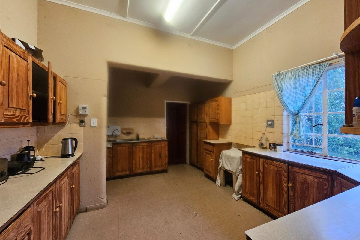 A dated kitchen featuring wooden cabinetry, tiled splashbacks, and a functional layout with a window overlooking the exterior.