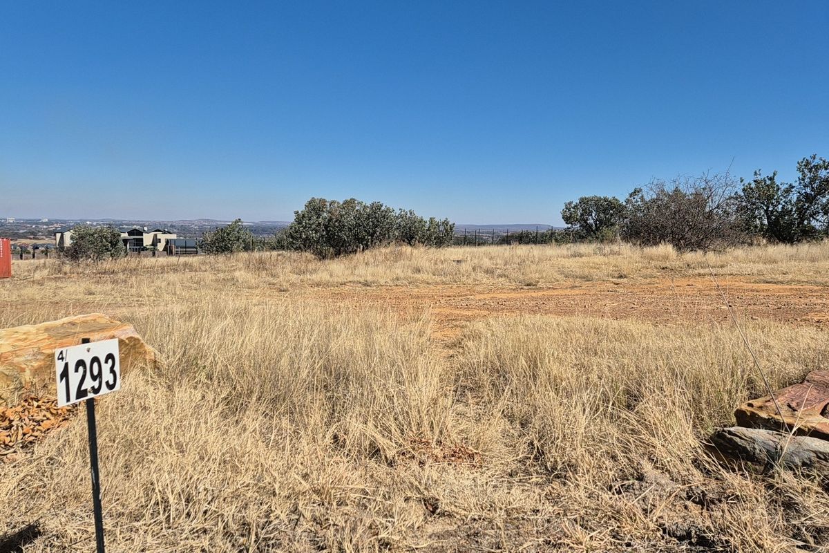 A view of a vacant residential plot featuring natural dry grass and surrounding landscape, suitable for future development.