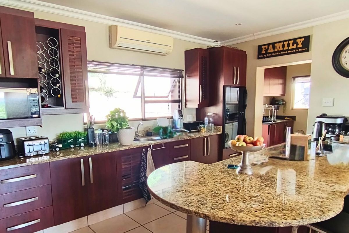 A functional kitchen featuring dark wood cabinetry, granite countertops, a central island, and an integrated air conditioning unit.