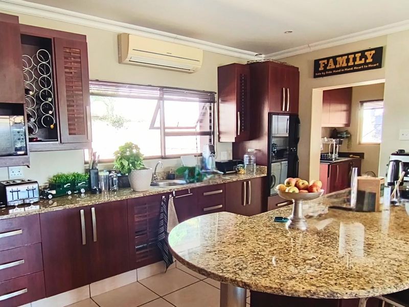 A functional kitchen featuring dark wood cabinetry, granite countertops, a central island, and an integrated air conditioning unit.
