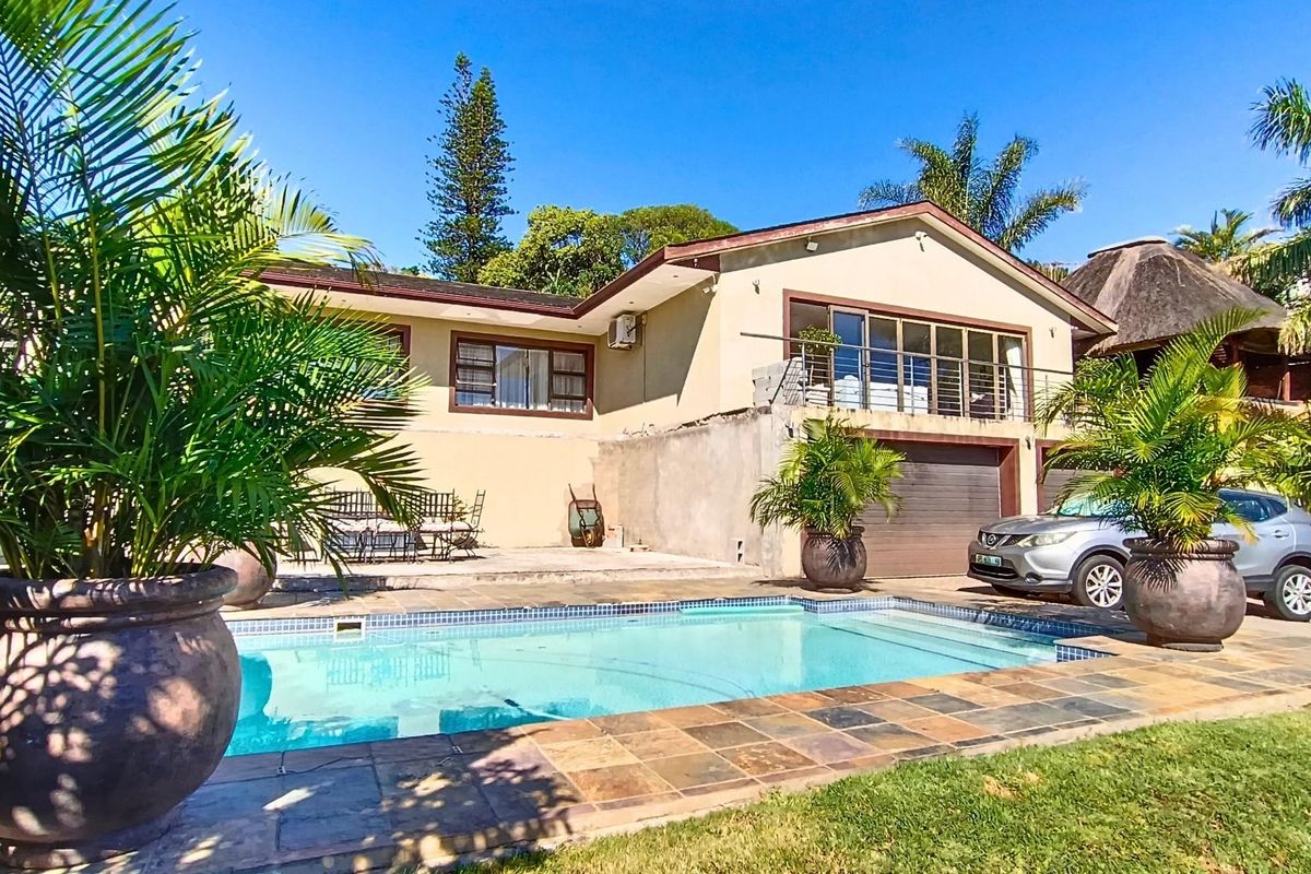 Rear exterior view of the house featuring a swimming pool, paved patio area, balcony, and integrated garage.