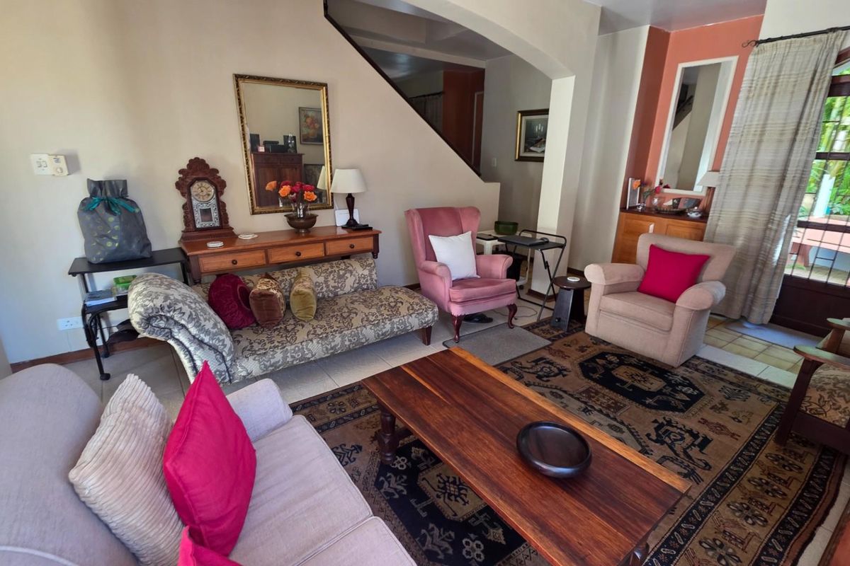 A living room area featuring a staircase, tiled flooring, and access to an outdoor patio through a glass-paneled door.