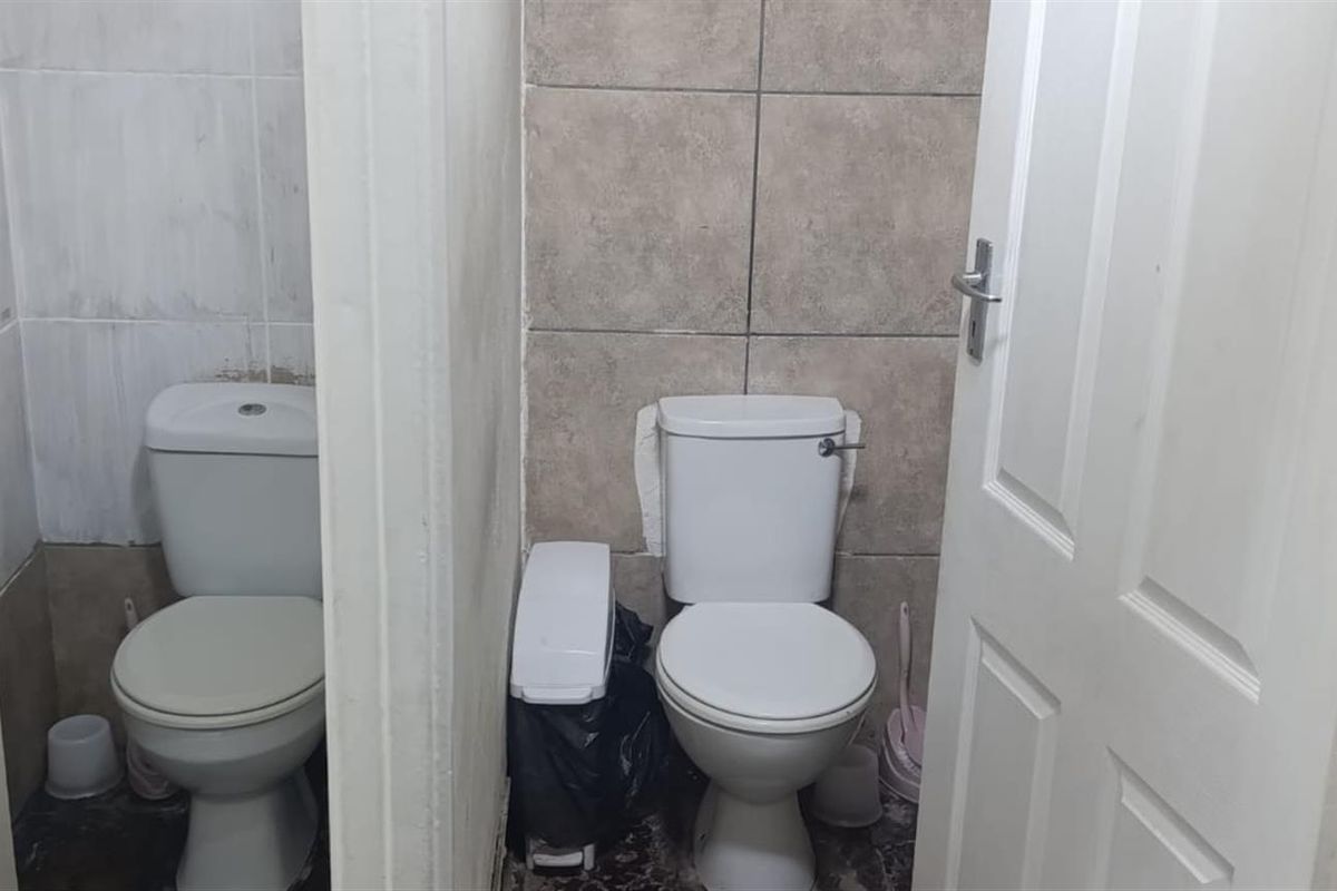 Two adjacent restroom stalls featuring standard white ceramic toilets and tiled wall finishes.
