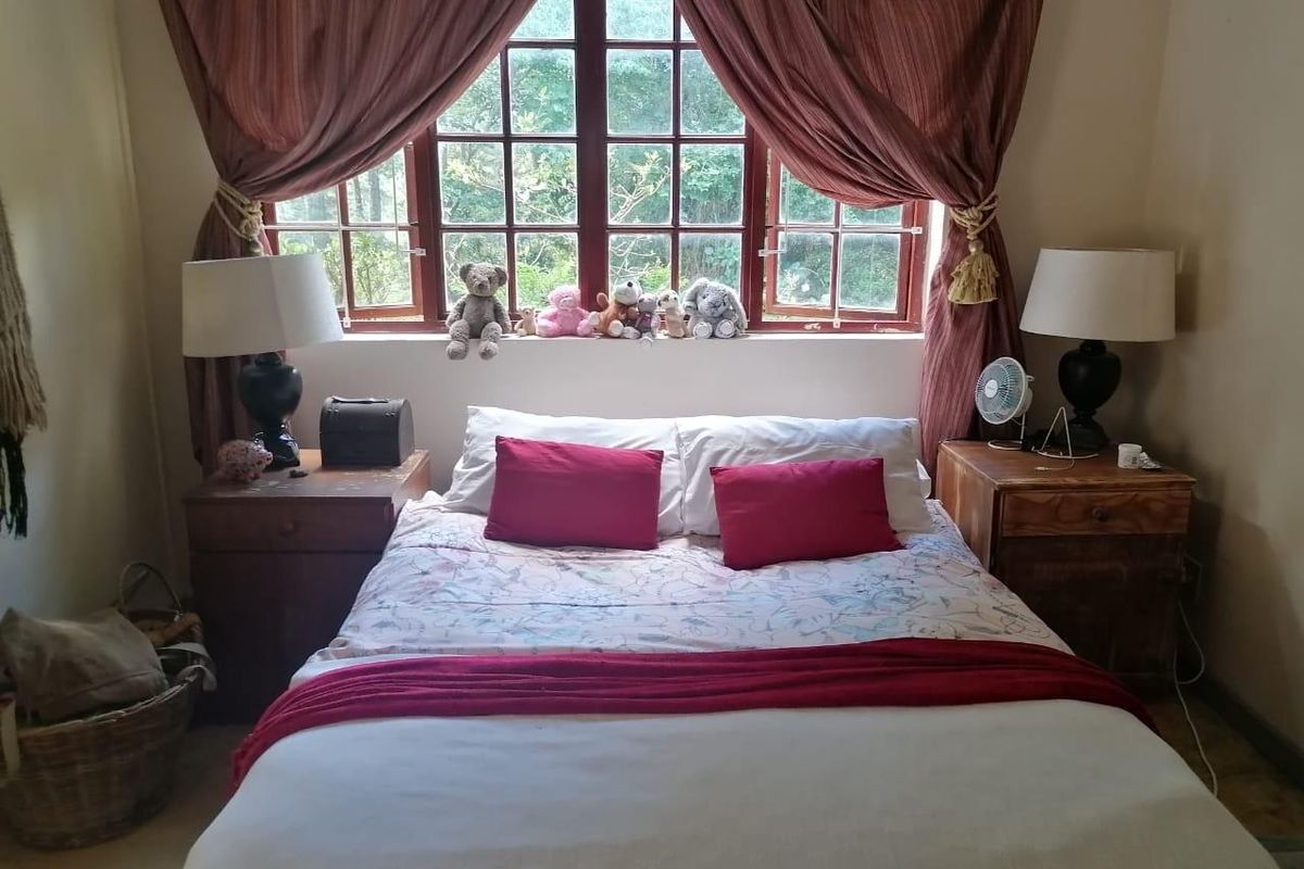 A cozy bedroom featuring a large multi-pane window with garden views, providing natural light and a peaceful atmosphere.