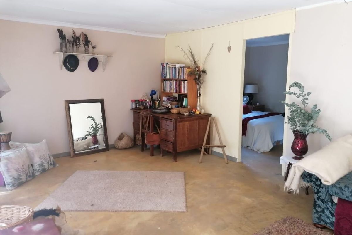 A living area featuring exposed concrete flooring and a doorway leading into an adjacent bedroom.