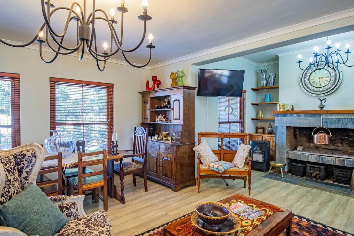 A cozy living and dining area featuring a prominent stone fireplace, built-in shelving, and wood-look flooring, creating a warm and inviting atmosphere.