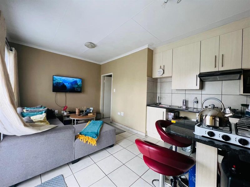 Open-plan living area featuring a compact kitchen with built-in cabinetry, granite countertops, and tiled flooring throughout.