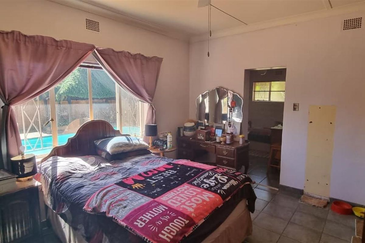 A bedroom featuring tiled flooring and a large window with views of the outdoor pool area.