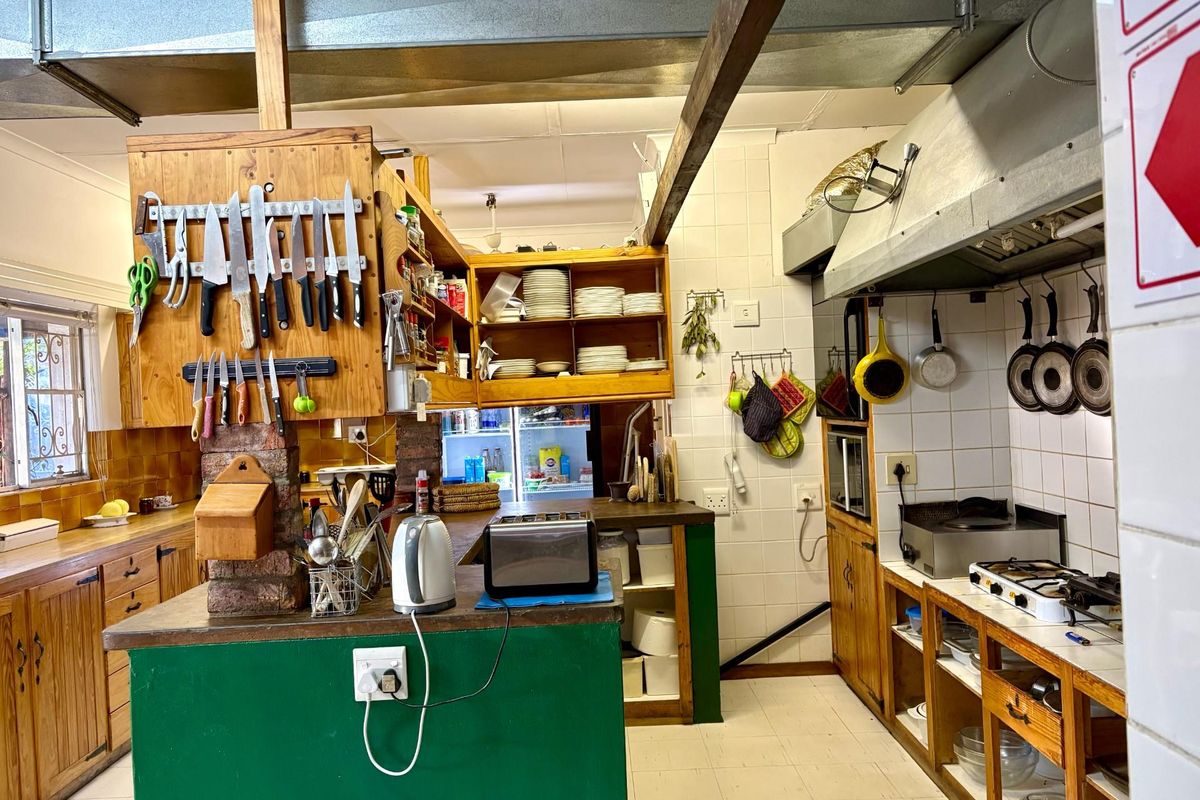 A functional kitchen area featuring wooden cabinetry, tiled splashbacks, a gas hob, and an integrated extractor fan, suitable for guest house operations.