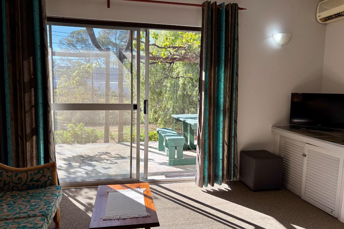 A living room featuring a large sliding glass door that opens onto a private patio area with garden views.