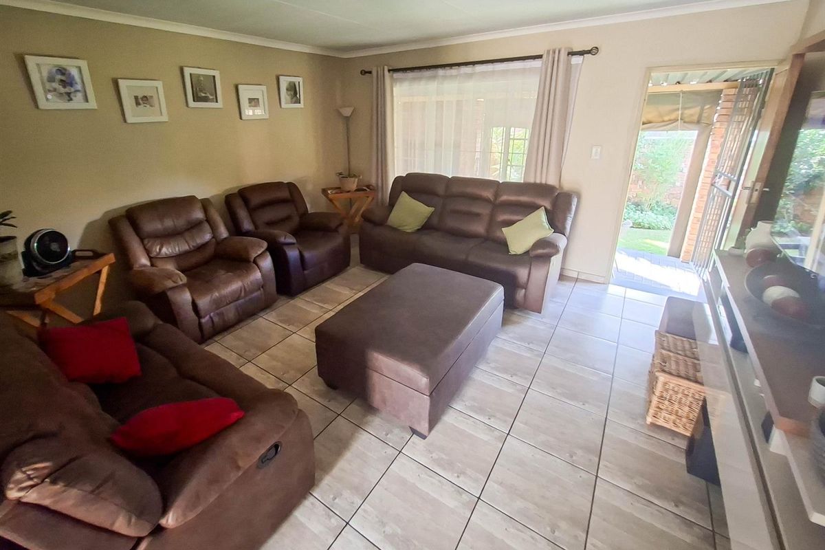 A spacious living room featuring neutral tiled flooring, large windows for natural light, and direct access to an outdoor patio area.